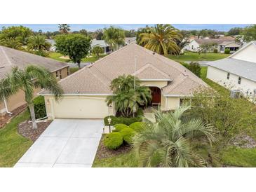 Charming home boasts lush landscaping, a well-manicured lawn, and an attached two-car garage at 1222 Camero Dr, The Villages, FL 32159