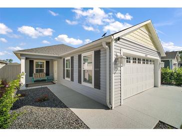 Charming single-story home featuring a two-car garage and well-maintained landscaping under a partly cloudy sky at 1251 Saranac Pl, The Villages, FL 32163