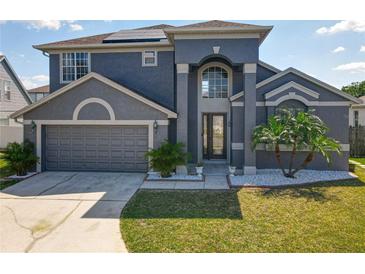 Beautiful two-story home with a well-manicured lawn, gray stucco, and a two-car garage at 13519 Bristlecone Cir, Orlando, FL 32828