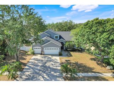Charming two-story home featuring a three-car garage, arched entry and lush, mature landscaping at 14305 Pine Cone Trl, Clermont, FL 34711