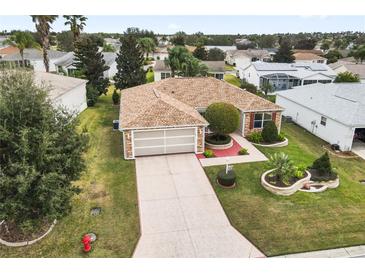Charming single-story home with a well-manicured lawn, brick accents, and a spacious two-car garage at 1526 Blueberry Way, The Villages, FL 32162