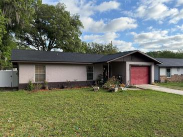 Charming single-story home featuring a red garage door and lush green lawn at 1805 Ne 29Th Pl, Ocala, FL 34479