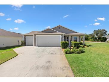 Charming single-story home with a two-car garage, well-maintained lawn, and beautiful landscaping at 2104 Iveywood St, The Villages, FL 32163
