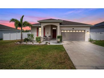 Charming single-story home featuring a well-manicured lawn, palm tree, and covered front porch at 37045 Scenic Ridge Dr, Grand Island, FL 32735