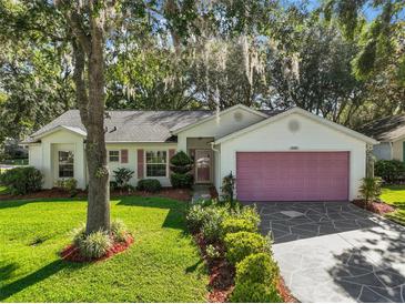 Charming single-story home with a well-maintained lawn, mature trees, and a patterned driveway leading to a two-car garage at 4349 River Ridge Dr, Leesburg, FL 34748
