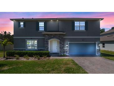 Charming two-story home showcasing stone accents, a well-manicured lawn, and blue shutters against a gray exterior at 524 Avila Pl, Howey In The Hills, FL 34737