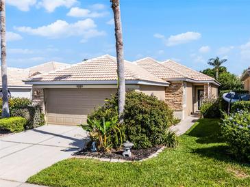 Inviting single-story home featuring a two-car garage, tile roof, stone accents, and lush landscaping at 9089 Saint Andrews Way, Mount Dora, FL 32757