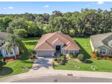 Beautiful one-story home featuring a brick paved driveway, well maintained landscaping, and a neutral color palette at 10069 Lake Miona Way, Oxford, FL 34484