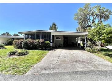 Cozy home featuring a screened-in porch, driveway with covered parking, and well-maintained landscaping at 104 Valencia Cv, Leesburg, FL 34748