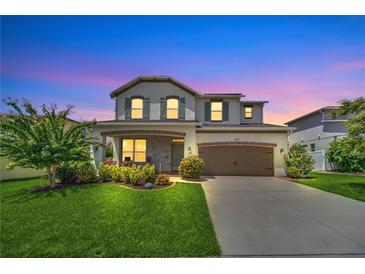 Charming two-story home with lush landscaping, brick accents, and a spacious two-car garage at dusk at 1281 Gatewood Ave, Minneola, FL 34715