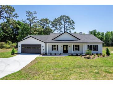 Charming single-story home with a well-manicured lawn, black accents, and an attached two-car garage at 155 W C-466, Lot # 1 W C 466, Oxford, FL 34484