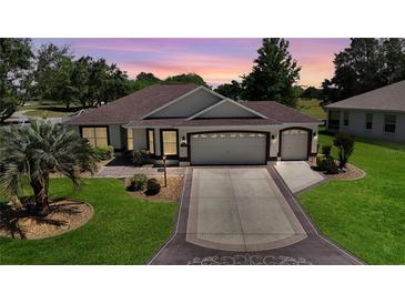 Beautiful single-story home boasts a three-car garage and an inviting, well-manicured front lawn at 17194 Se 85Th Willowick Cir, The Villages, FL 32162
