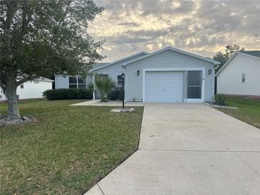 Charming single-story home featuring a well-manicured lawn, driveway, and attached garage at 1812 Sanibel Ct, The Villages, FL 32162