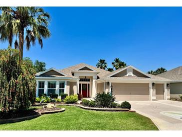 Charming single-story home featuring a well-manicured lawn, mature landscaping, and a three-car garage at 1985 Abordale Ln, The Villages, FL 32162