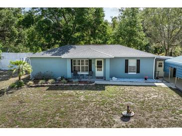 Inviting home featuring a cozy front porch with seating, complemented by lush greenery and mature landscaping at 201 W Mirror Lake Dr, Fruitland Park, FL 34731