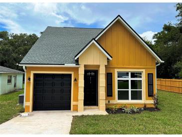 Charming one-story home showcasing yellow siding, a black garage door, and a well-maintained lawn at 217 S East St, Leesburg, FL 34748