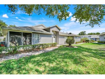 Charming home featuring a well-maintained lawn, beautiful light-gray siding, and a screened-in porch at 26736 Cash Ct, Leesburg, FL 34748