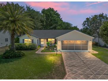 Charming single-story home featuring a well-manicured lawn, mature palm tree, and a patterned driveway at 511 Chula Vista Ave, The Villages, FL 32159