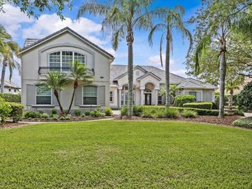 Beautiful home featuring lush green grass, swaying palm trees, manicured shrubs and tasteful landscaping around the property at 5530 Oxford Moor Blvd, Windermere, FL 34786