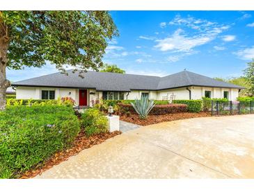 Charming one-story home featuring mature landscaping, painted brick, dark roof and a welcoming red front door at 657 Riverpark Cir, Longwood, FL 32779