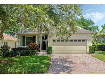 Charming single-story home featuring a brick driveway, attached garage, and mature landscaping with a tree with Spanish moss at 791 Wolf Creek St, Clermont, FL 34711