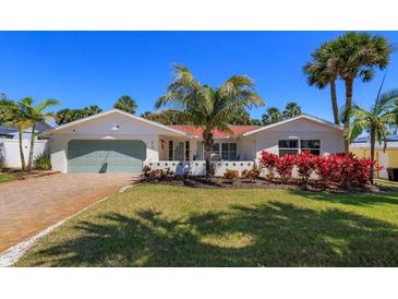 Charming single-story home with a well-manicured lawn, colorful plants, and a serene tropical ambiance at 910 Locust St, New Smyrna Beach, FL 32169
