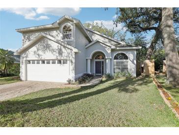 Charming two-story home featuring arched entryway, manicured lawn, and attached two-car garage at 981 Piedmont Oaks Dr, Apopka, FL 32703