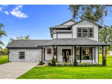 Charming two-story home featuring a welcoming front porch with rocking chairs and landscaped front yard at 10901 Island Grove Rd, Clermont, FL 34711