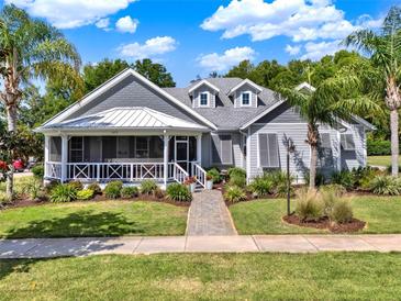 Charming single-story home featuring a inviting front porch, beautiful landscaping and mature palm trees at 1172 Fiesta Key Cir, Lady Lake, FL 32159