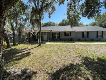 Charming one-story home featuring a covered porch and well-maintained front yard with mature trees and attractive landscaping at 1650 Sundance Dr, St Cloud, FL 34771