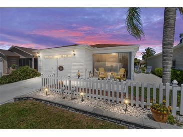 Charming exterior of a single-story home with a white picket fence and manicured lawn at dusk at 2063 Thornton Ter, The Villages, FL 32162