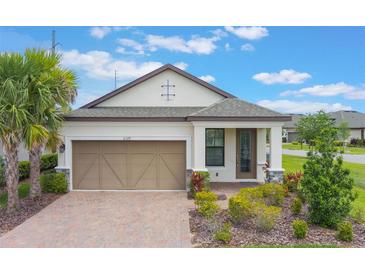Charming one-story home with a well-manicured lawn, paver driveway, and a two-car garage at 2129 Palm Tree Dr, Poinciana, FL 34759