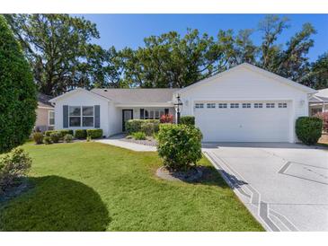 Charming single-story home with well-manicured lawn, mature trees, and a two-car garage at 2482 Ansley Path, The Villages, FL 32162