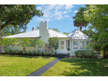 Charming one-story home featuring a metal roof, lush landscaping, and a well-manicured front lawn at 306 N Clayton St, Mount Dora, FL 32757