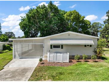 Charming single-story home with a screened carport and well-manicured lawn, perfect for relaxing outdoors at 34407 Island Dr, Leesburg, FL 34788