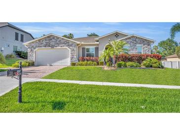 Beautiful single-story home with stone accents, lush landscaping, and a well-manicured lawn at 4060 Longbow Dr, Clermont, FL 34711