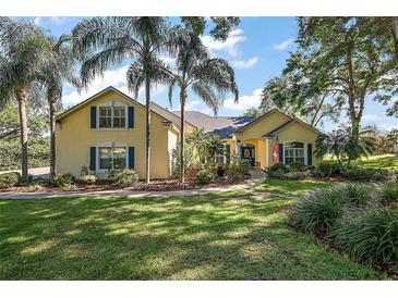Charming yellow two-story home featuring mature landscaping, a welcoming walkway, and beautiful curb appeal at 848 Hawk Lndg, Fruitland Park, FL 34731
