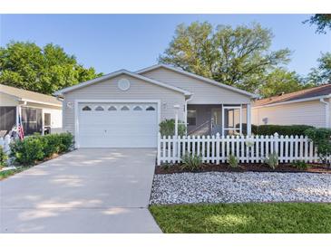 Charming single-story home with a white picket fence, well-maintained lawn, and a one car garage at 9325 Se 172Nd Garden St, The Villages, FL 32162
