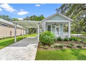 Charming cottage-style home features a covered front porch, carport, and attractive landscaping at 12129 Grand Oak Ln, Oxford, FL 34484