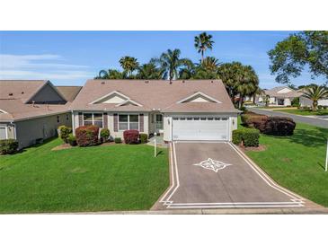 Charming home with a two-car garage, decorative driveway, and beautiful landscaping at 1743 Landrum Ln, The Villages, FL 32162