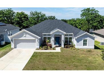 Charming single-story home featuring a well-manicured lawn and a classic two-car garage at 1922 Angel Fish Loop, Leesburg, FL 34748