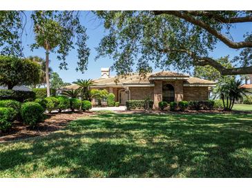 Beautiful brick home featuring a lush lawn, manicured landscaping, and a clay tile roof at 301 Waterwood Dr, Yalaha, FL 34797