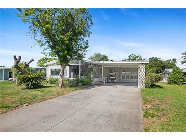 Charming single-story home with a covered carport and beautiful landscaping under a clear blue sky at 432 King Way, Tavares, FL 32778