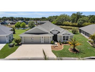 Charming single-story home featuring a manicured lawn, three-car garage, and a picturesque pond view at 5220 Horsford Path, The Villages, FL 32163