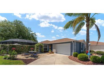 Charming home featuring a well-manicured front yard, inviting patio, and a two-car garage at 850 Oviedo Rd, Lady Lake, FL 32159