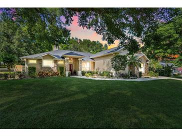 Beautifully landscaped single-Gathering home with stone accents, red door and mature trees in a serene setting at 10851 Lantana Crst, Clermont, FL 34711