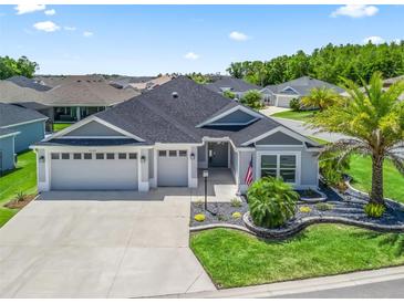 Charming single-story home boasts a three-car garage and beautifully landscaped front yard with a palm tree at 2006 Oppenheimer Ct, The Villages, FL 34762