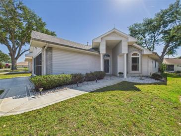Charming single-story home featuring a manicured lawn, decorative rock landscaping, and a welcoming entryway at 21707 Queen Mary Ct, Leesburg, FL 34748