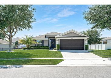 Charming single-story home featuring a well-manicured lawn, mature trees, and a two-car garage at 274 Giovani Blvd, Clermont, FL 34715