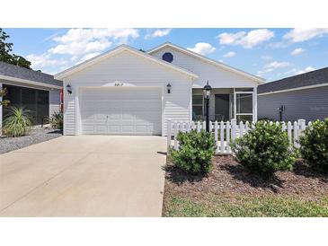 Charming single-story home featuring a two-car garage, white picket fence, and well-manicured landscaping at 5817 Valente Ct, The Villages, FL 32163